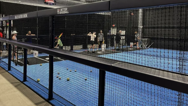 Square rail padding on indoor batting cage frame with custom facility branding