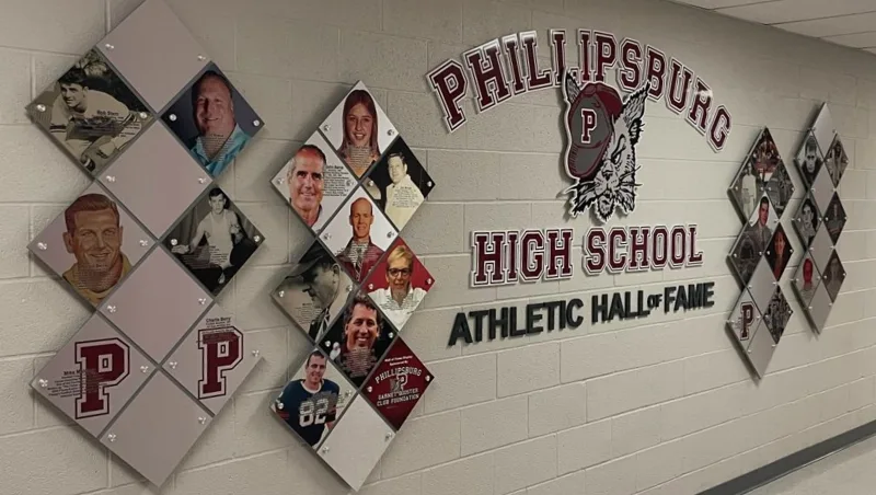 Athletic hall of fame display at Phillipsburg High School with diamond-shaped photo panels of inducted athletes surrounding a wildcat mascot graphic and "P" lettermarks