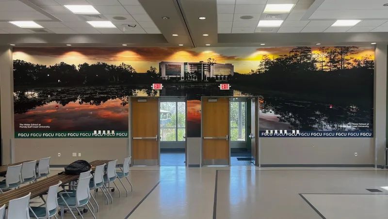 Adhesive vinyl wall mural at Florida Gulf Coast University showing a sunset over water with The Water School building reflected