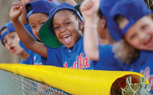 Athletic gold FenceCrown poly topper capping a chain-link outfield fence at a youth baseball field