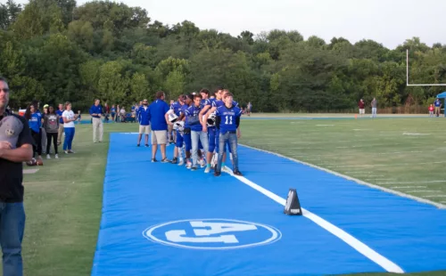 Royal blue ArmorMesh custom football sideline tarp providing sideline turf protection at Anna Jonesboro field
