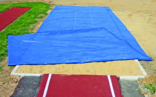 FieldSaver weighted long jump sand pit cover folded back to reveal built-in weighted perimeter edge that secures jump pit cover without stakes or sandbags