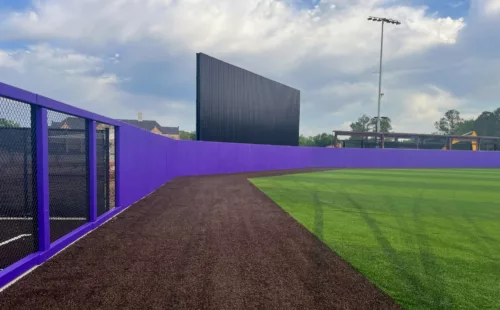 Purple custom stadium padding installed on baseball outfield wall and fence at University of Northern Alabama showing protective padding coverage