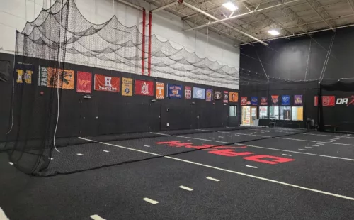 Retractable indoor batting cage kit with ceiling suspension in open position at Dash multi-sport training facility