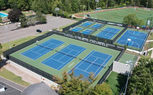 Aerial view of tennis courts surrounded by custom printed privacy screens featuring facility branding at The Courts at Liberty Park in North Caldwell