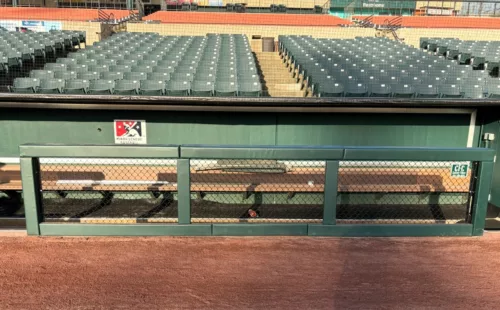 Green custom fence rail and post padding installed on a dugout rail at a baseball stadium