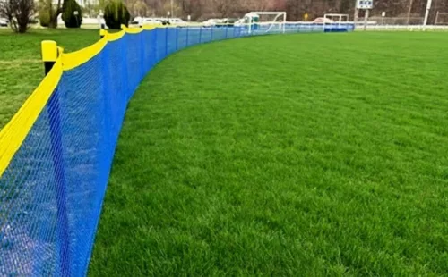 Blue portable sports fencing used as Grand Slam fencing along a baseball outfield athletic boundary