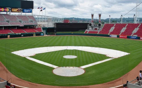 White skin tarps covering the base paths and infield dirt of a baseball diamond, with round covers on the pitcher's mound and home plate in an empty ballpark