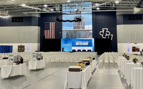Gray GymGuard vinyl gym floor cover deployed full-court at John Carroll University, with rows of folding chairs and catering tables on the protected floor.